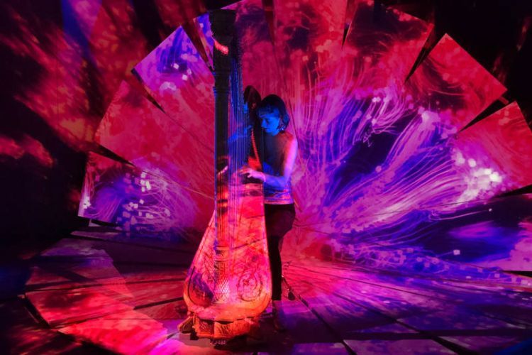 Harpist performs with colourful video projections all around them